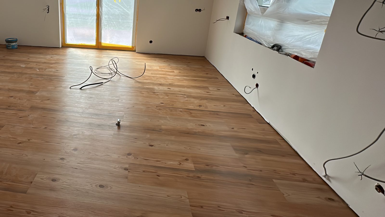 Fertig verlegter Vinylboden in heller Holzoptik, Planken bis zur Wand