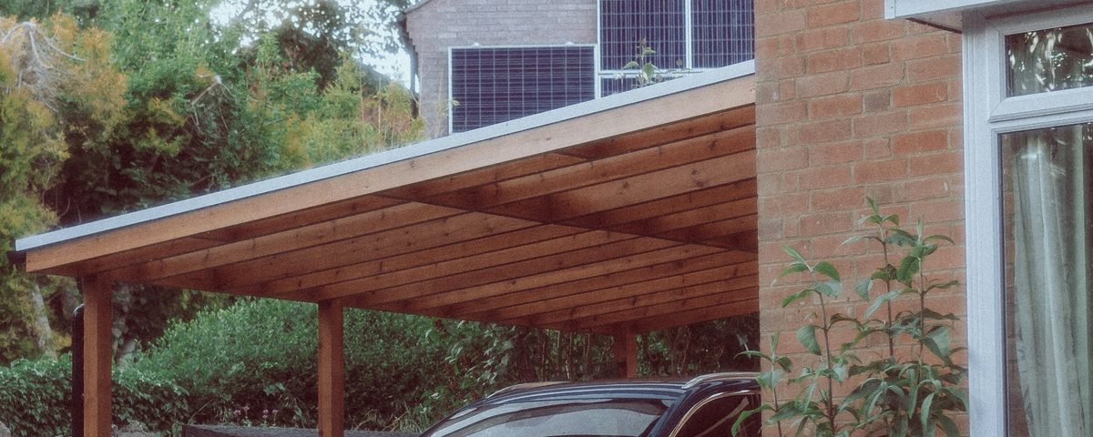 Carport aus Holz mit Pultdach, am Haus angebaut; die Rinne sitzt am tiefen Dachrand