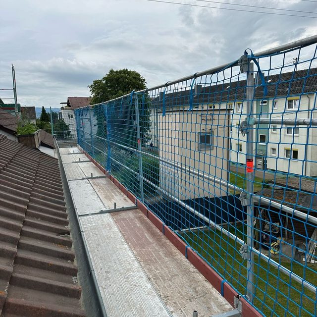 Blick von der obersten Ger&uuml;stlage: Belag direkt an der Dachrinne, rechts ein blaues Netz