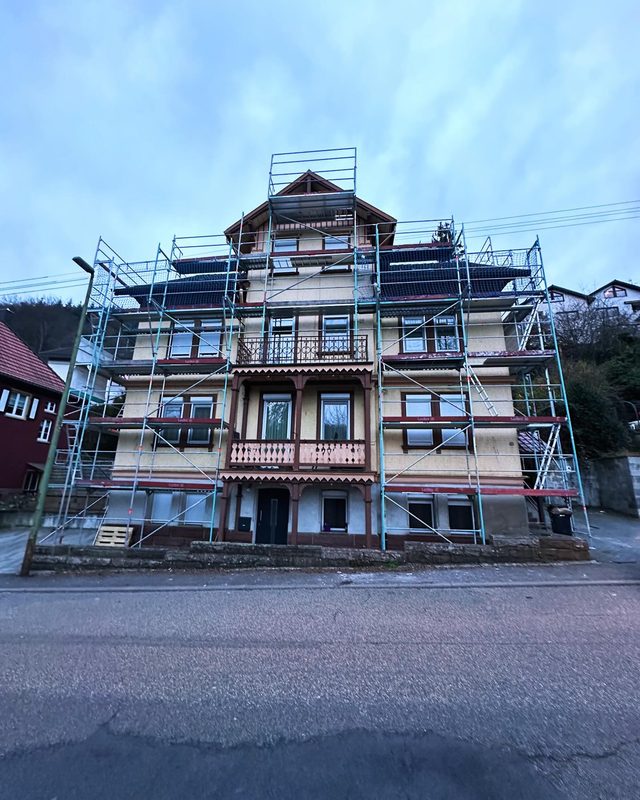 Altes Mehrfamilienhaus mit verzierten Holzbalkonen, Ger&uuml;st &uuml;ber alle Geschosse bis zum Dach