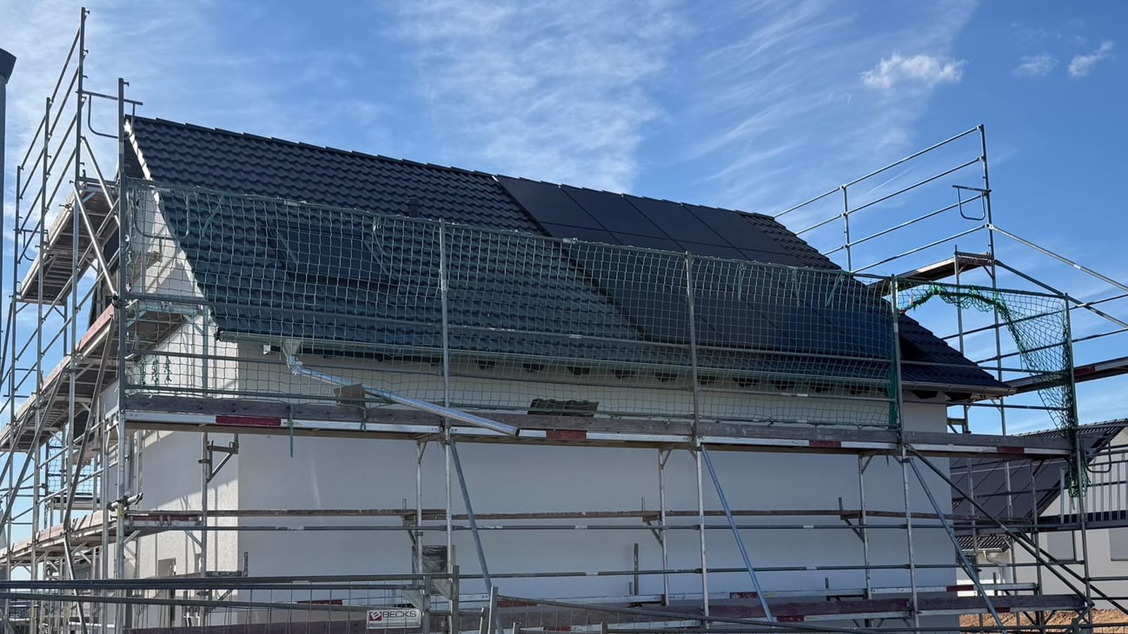 Neubau in Oedheim im September 2026: Das Dach ist gedeckt, das Ger&uuml;st steht, die ersten Solarmodule liegen am First.
