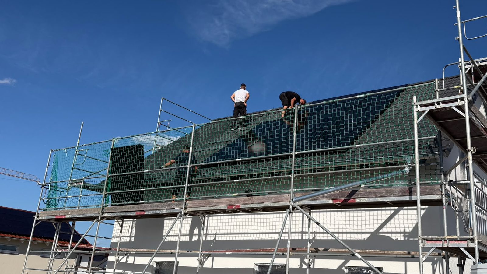Zwei Monteure montieren im September 2026 auf einem Oedheimer Neubau Solarmodule am Dachfirst.