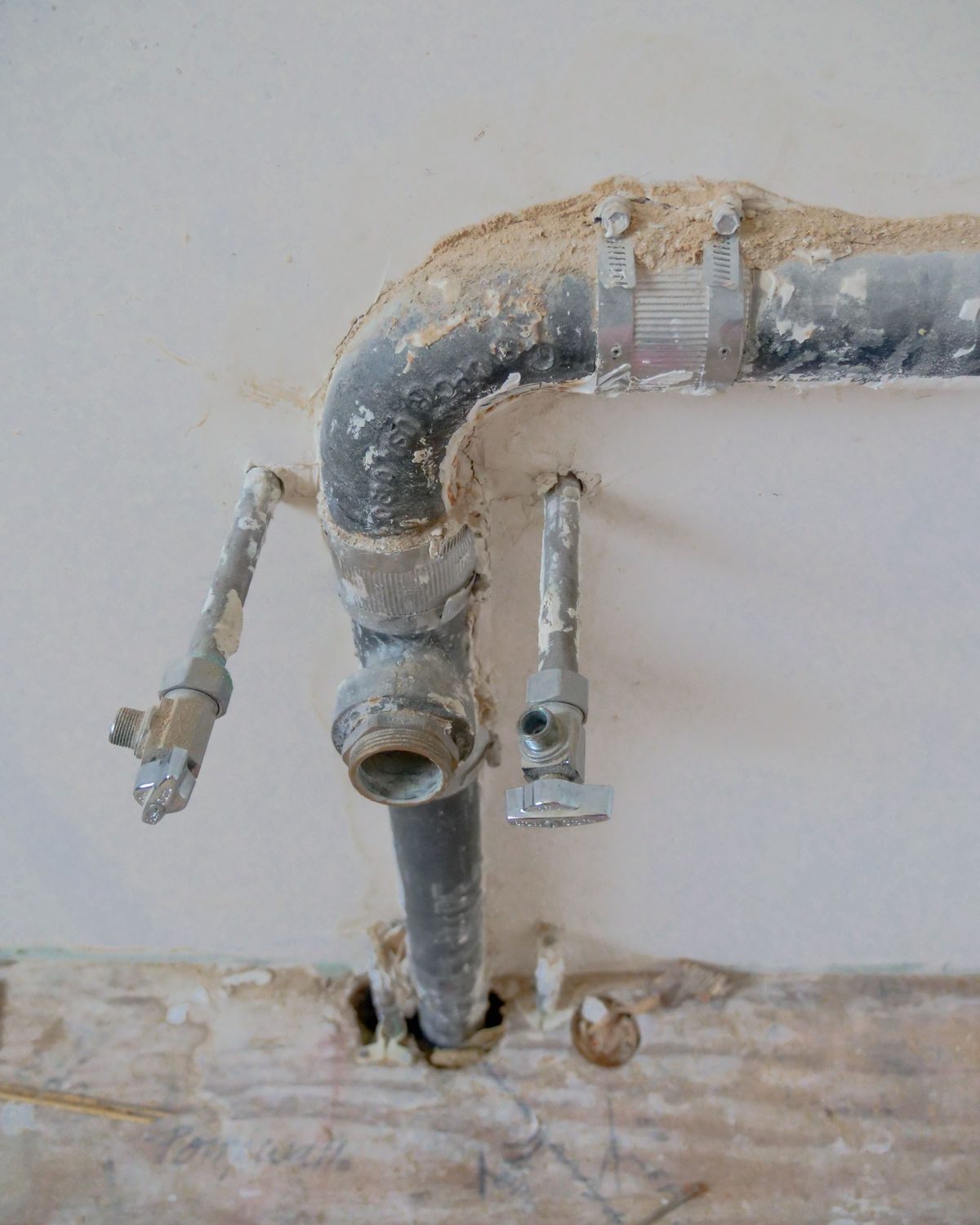 Alte Wasserleitung aus verzinktem Stahl mit korrodierten Verbindungen in einer ge&ouml;ffneten Wand