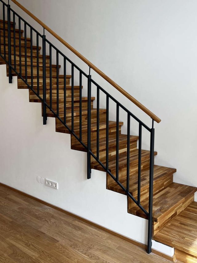 Gerade Treppe mit Holzstufen und Geländer aus senkrechten schwarzen Stäben