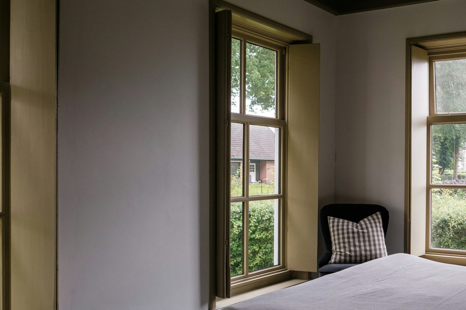 Ruhiges Schlafzimmer mit wei&szlig;er Bettw&auml;sche vor einem geschlossenen Fenster, durch das Tageslicht f&auml;llt